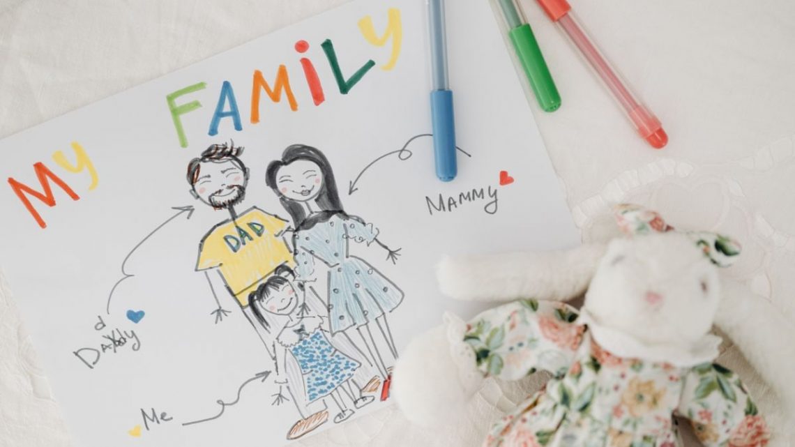 A child's colorful family drawing next to pens and a plush toy on a white surface.